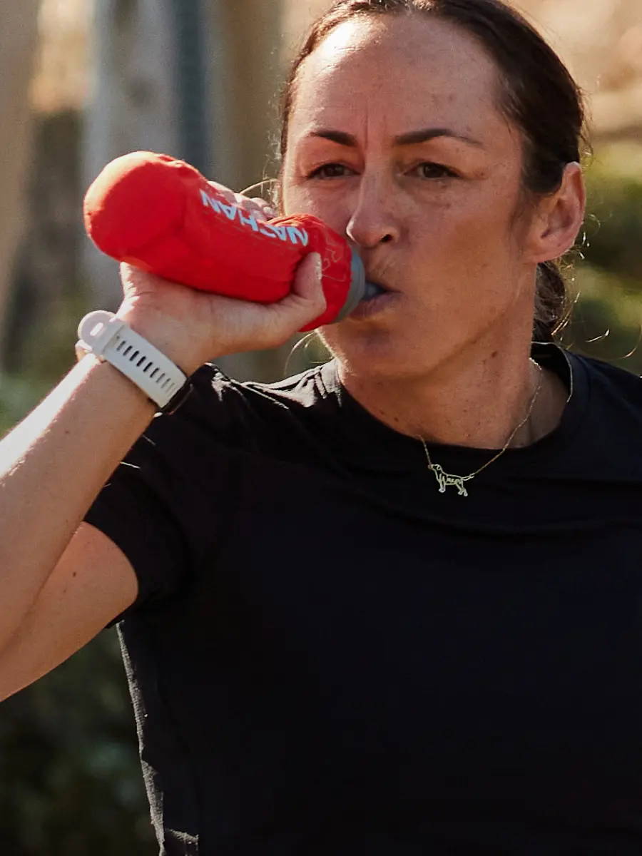 Female runner drinking from a Nathan handheld water bottle.
