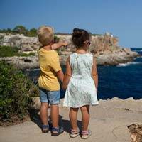 Two young kids holding hands looking at the water and surroundings