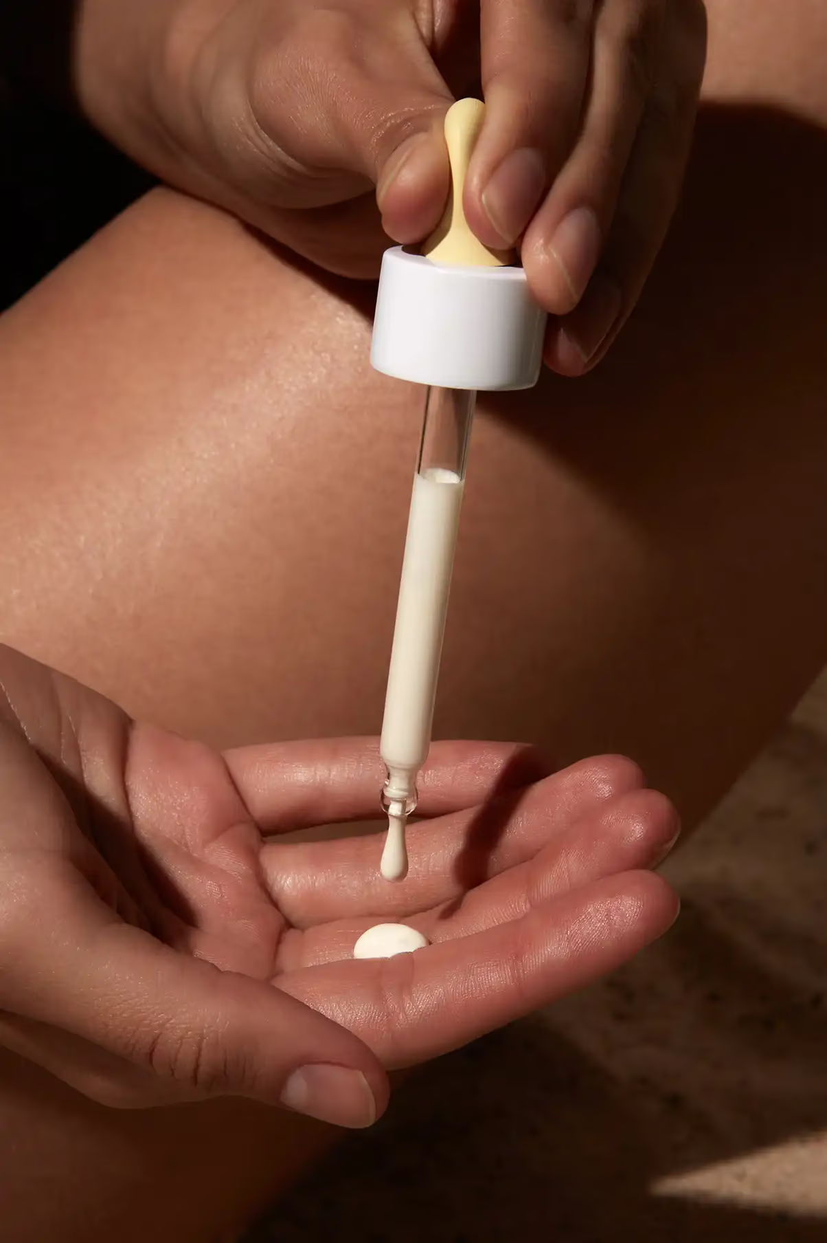 A person applying liquid from a dropper onto their palm.