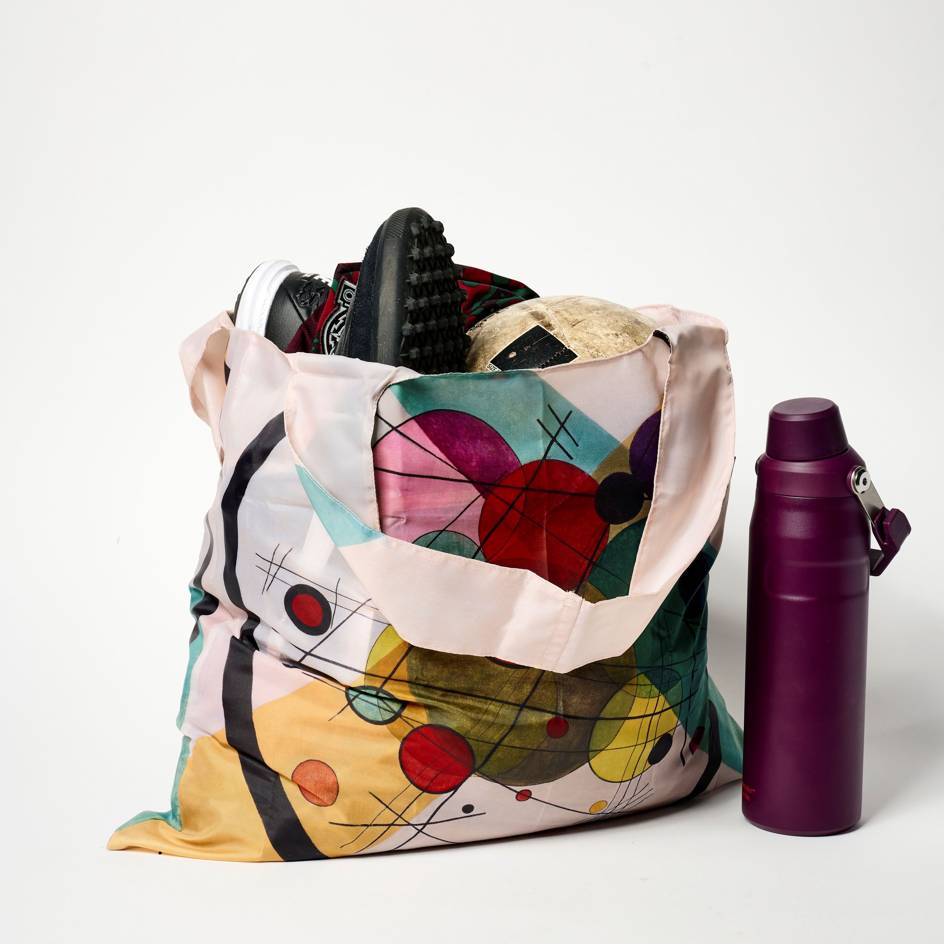 Colorful bag with shoes and a purple water bottle.