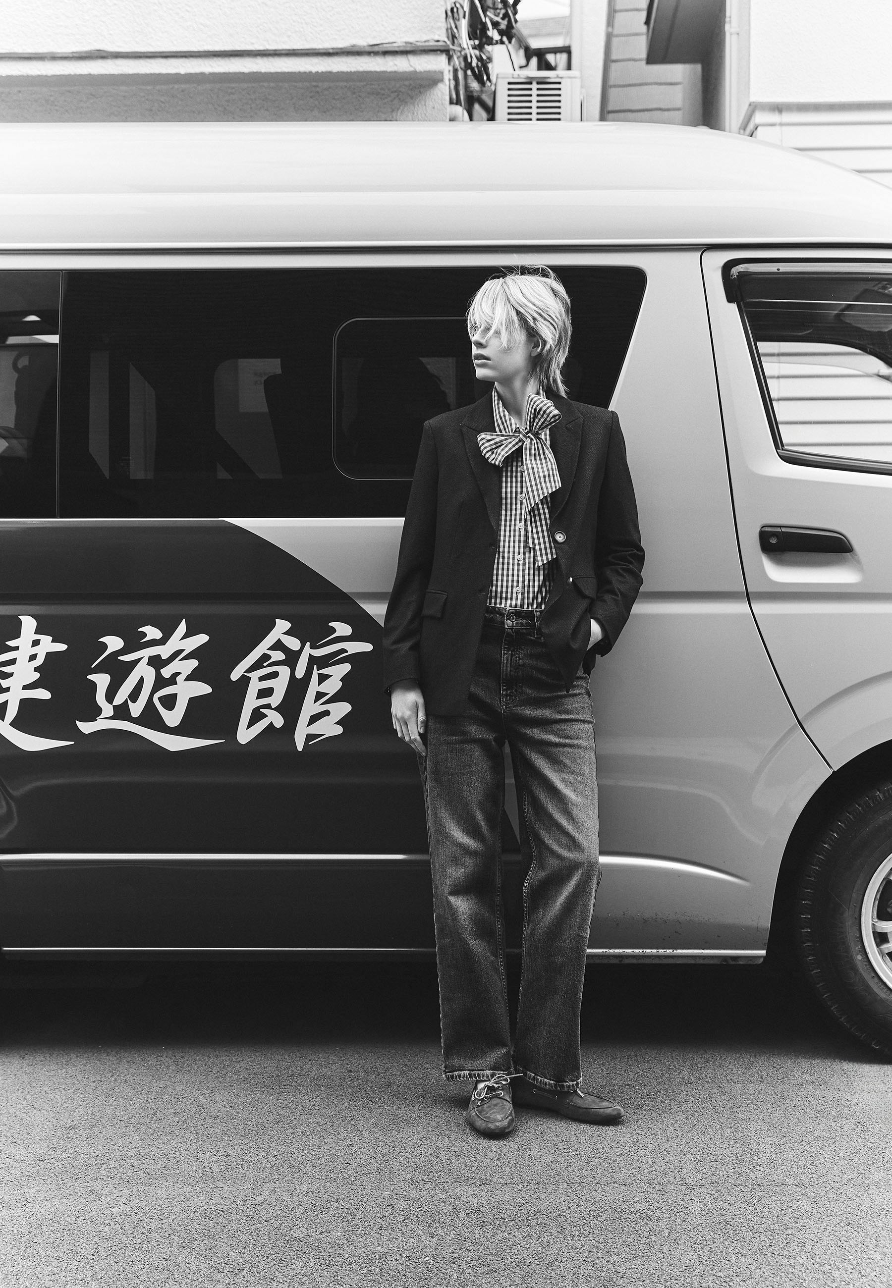 Person standing next to a van with text in an urban setting.