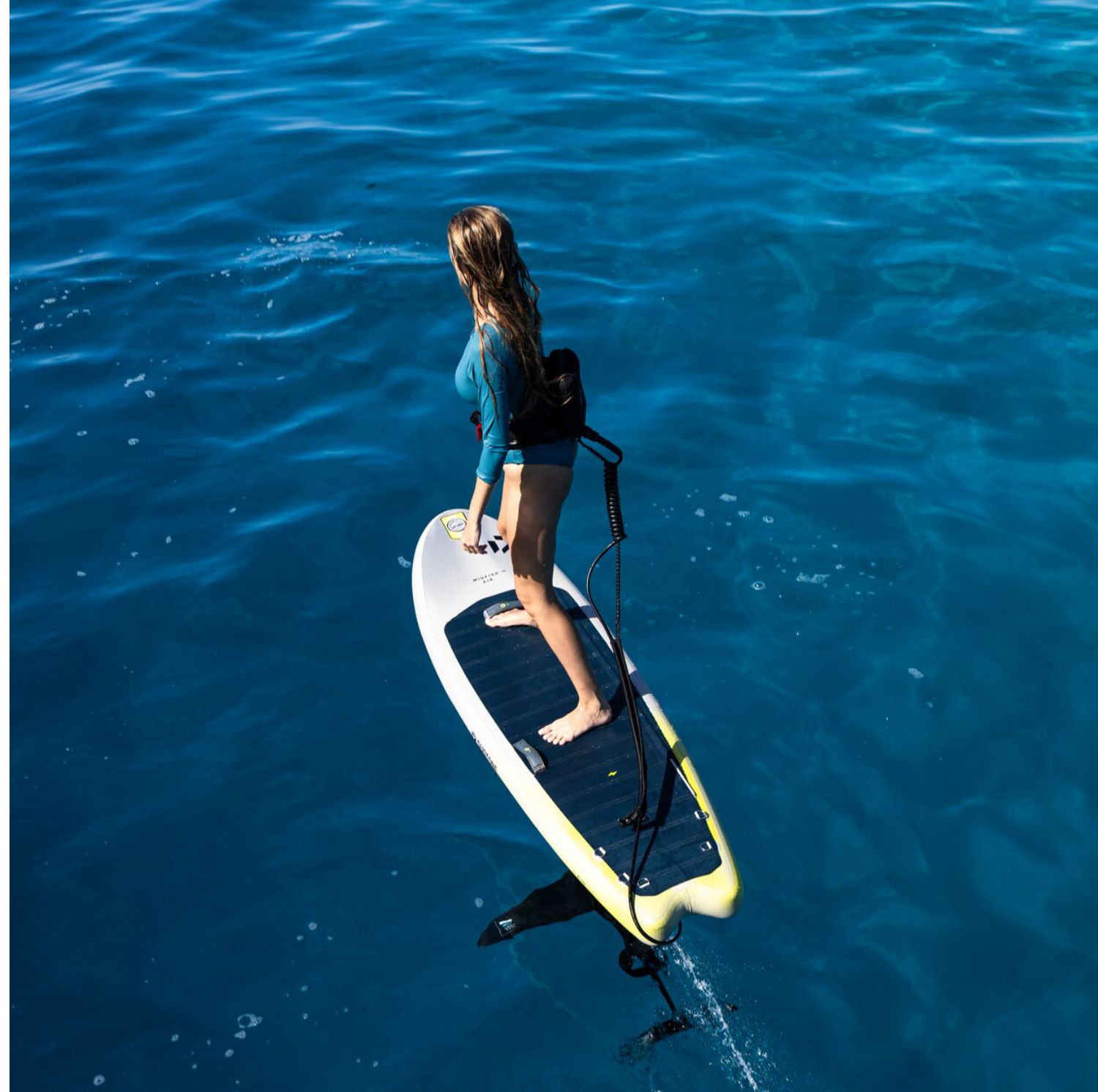 Person on a surfboard gliding over blue water.
