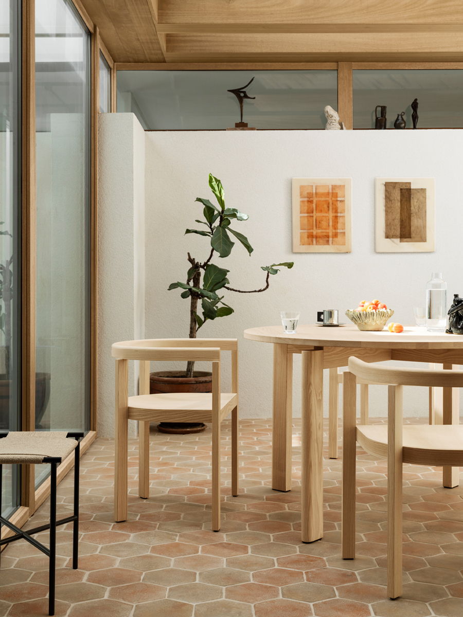 Modern Fritz Hansen dining area with wooden furniture and plants, featuring artwork on the walls.