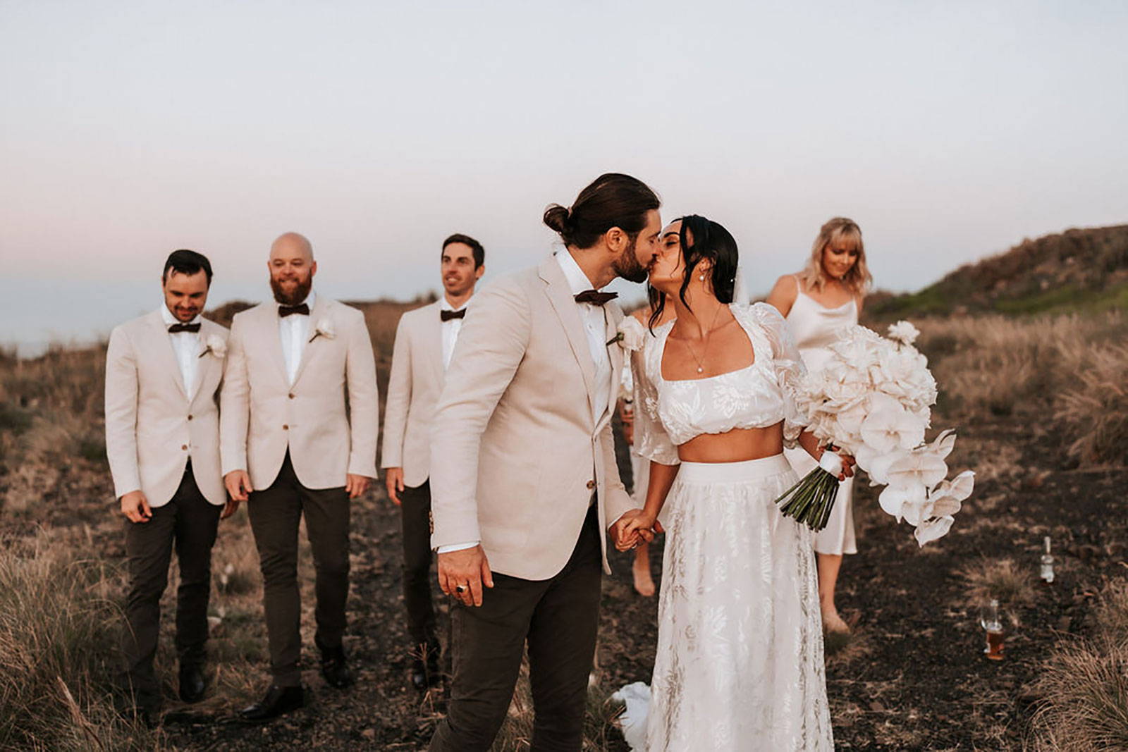 Bride and Groom sharing a kiss with Bridal party in background