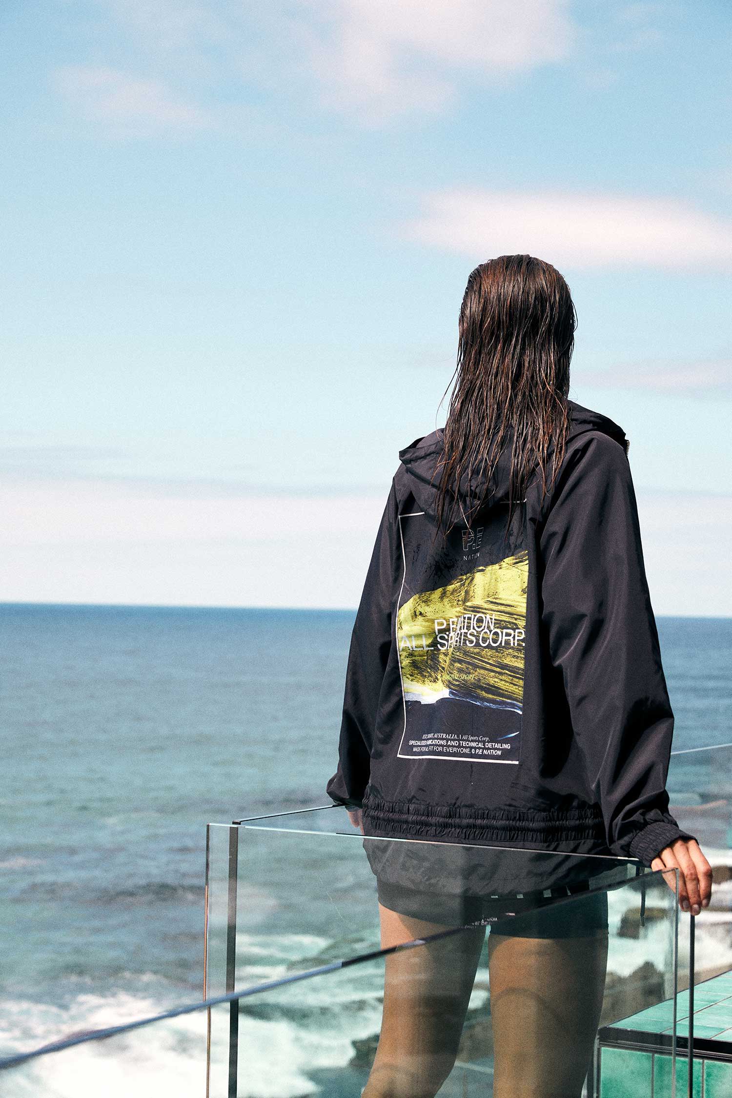 Girl in a hoodie standing next to the ocean