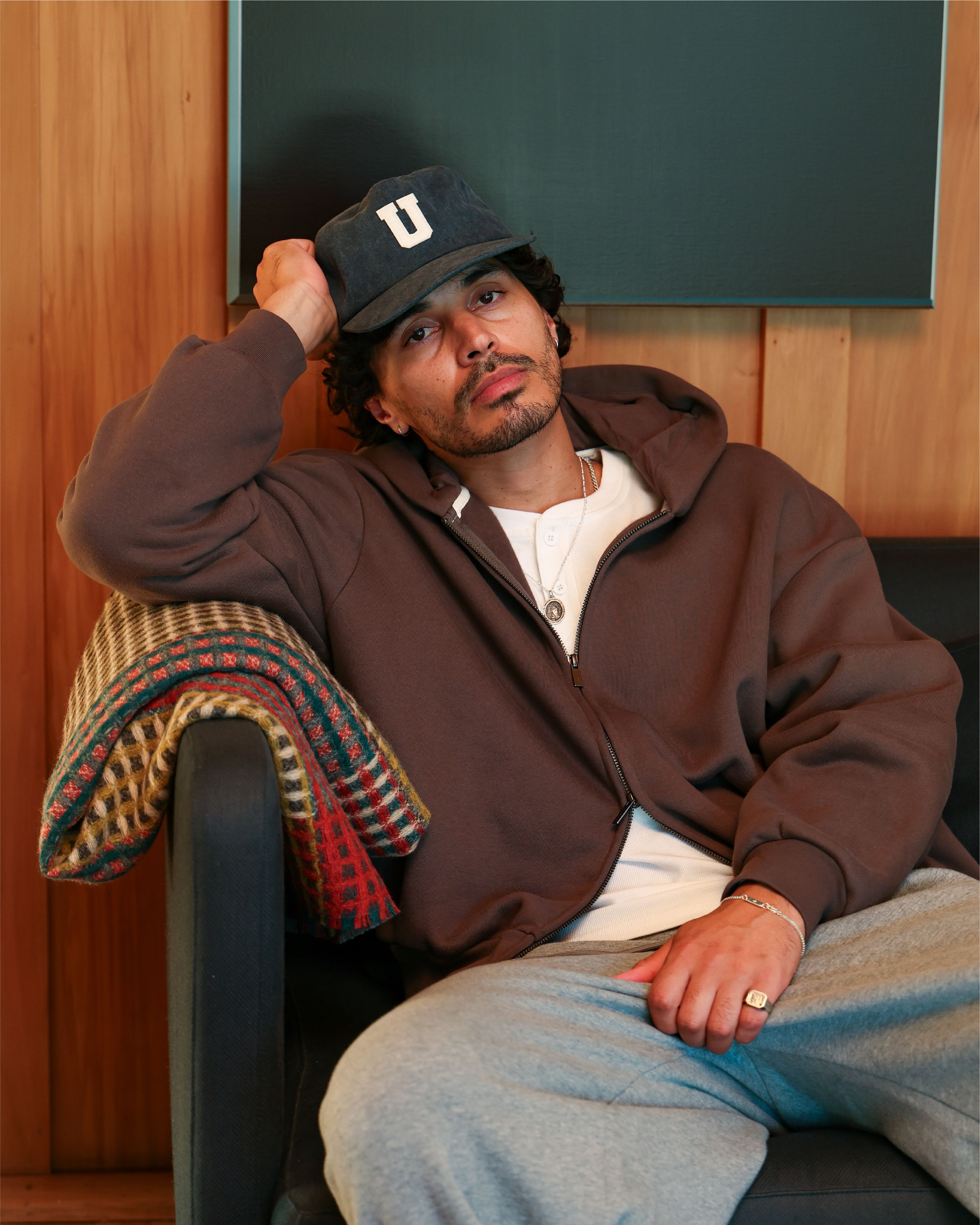 Man in casual attire sitting on a couch, looking relaxed.