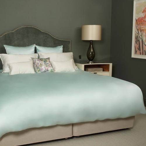 Cojín de pura seda estampado y blanco sobre una cama de seda color pastel