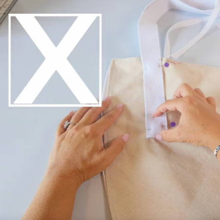 Box stitch with X through it securing cotton belting handle to the flower bag
