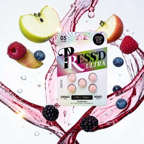 Colorful packaging of TRESSED ULTRA pills surrounded by fruits and liquid splashes.