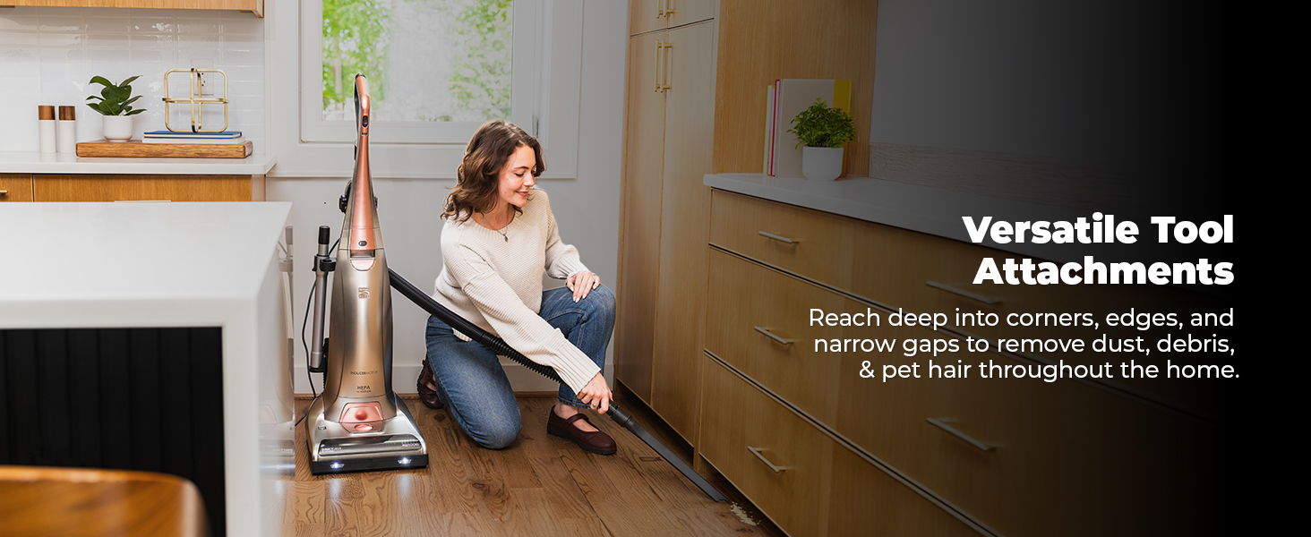 Woman using a vacuum with versatile tool attachments in a kitchen setting.