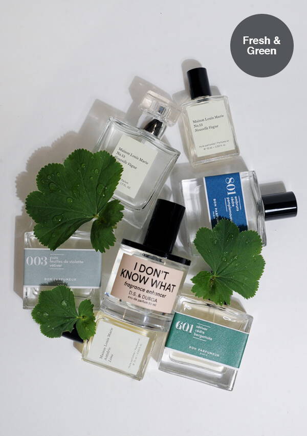 A styled flat lay image of multiple fresh and green fragrances by D.S. & Durga, Maison Louis Marie and Bon Parfumeur amongst fresh dewy green leaves.
