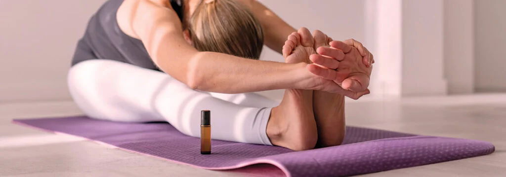 A person stretching on a yoga mat, holding their feet.