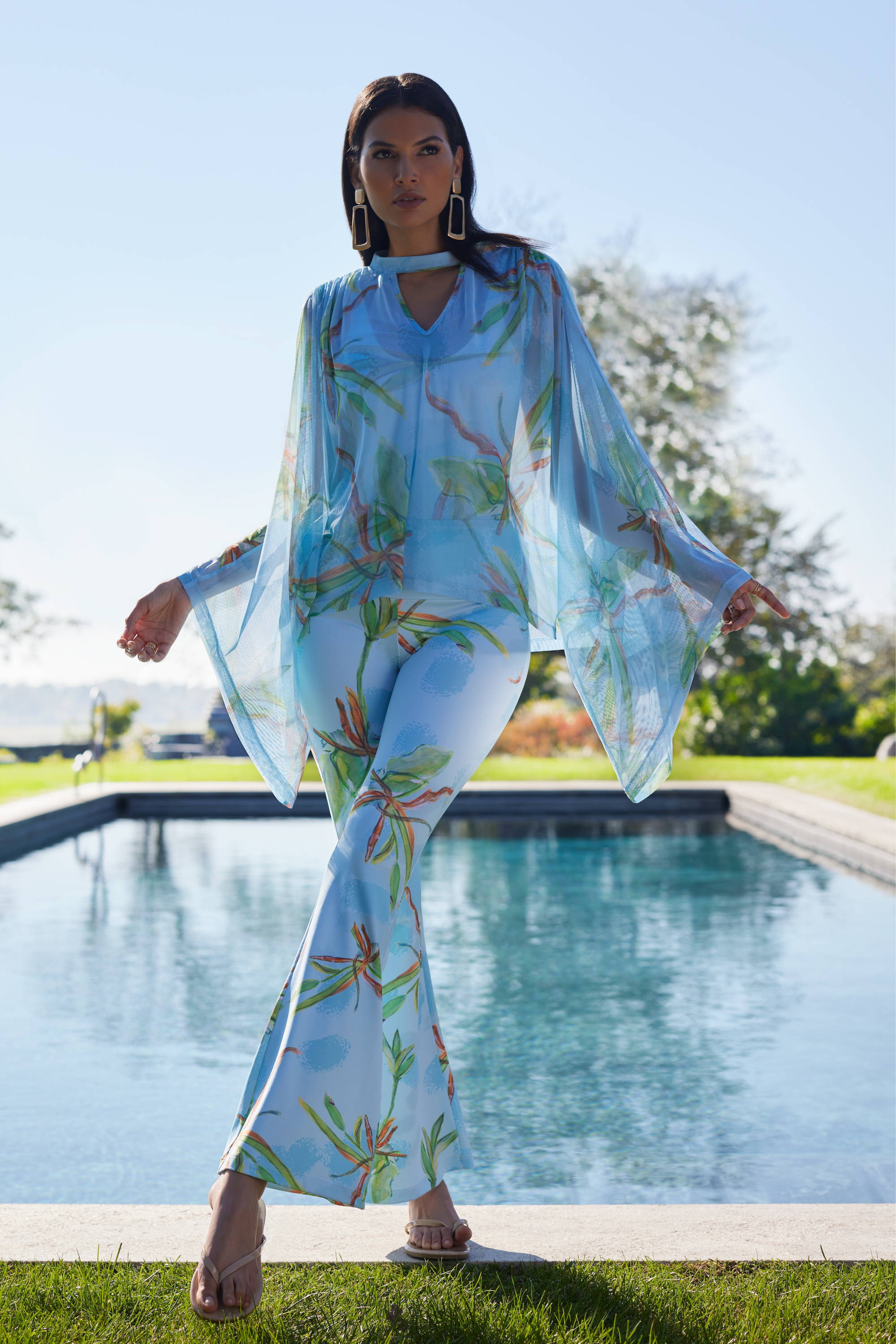 Woman wearing mesh tunic blouse bathing suit cover up with blue green stretch knit pants by a pool by Ala von Auersperg