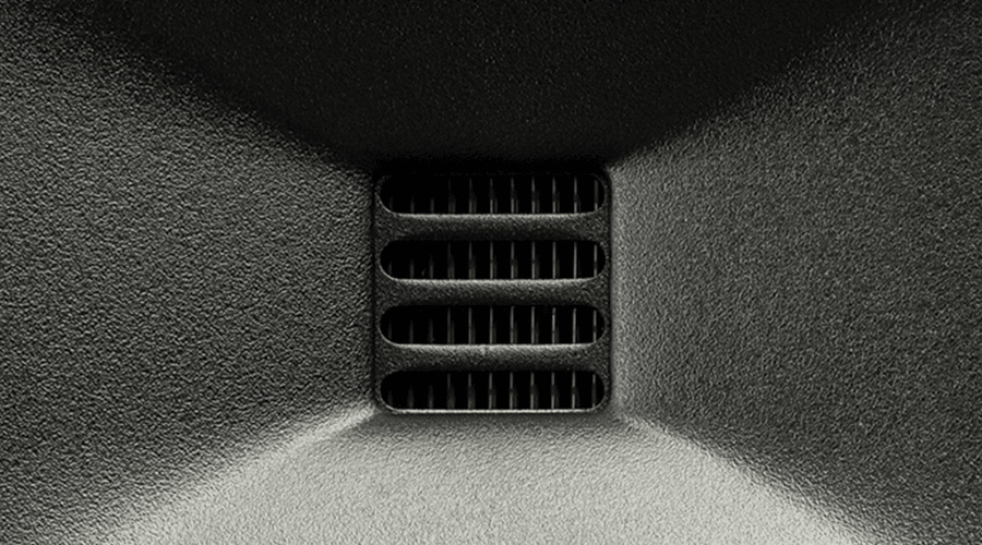 Close-up of a black vent with horizontal slats against a dark background.