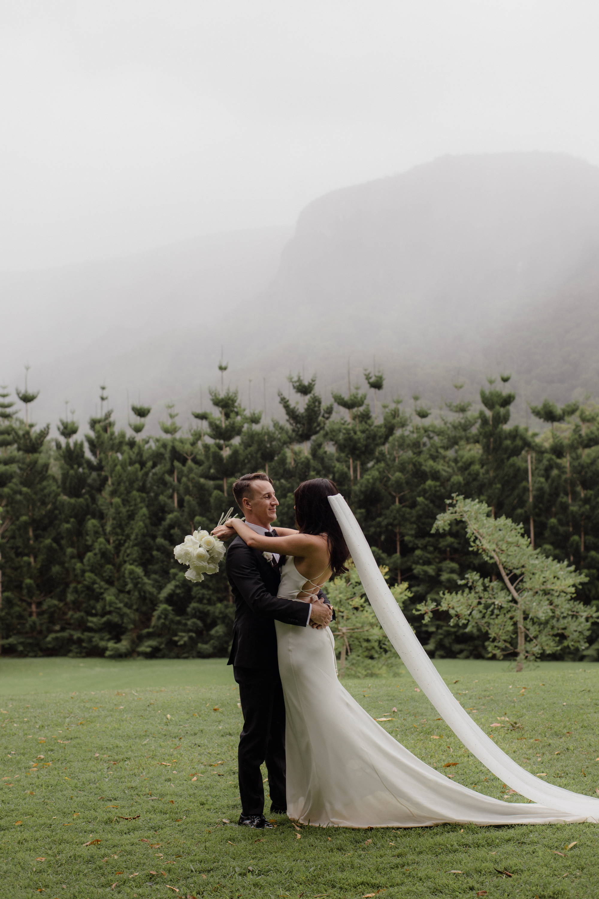 Bride wearing silk dress and tulle veil with her groom