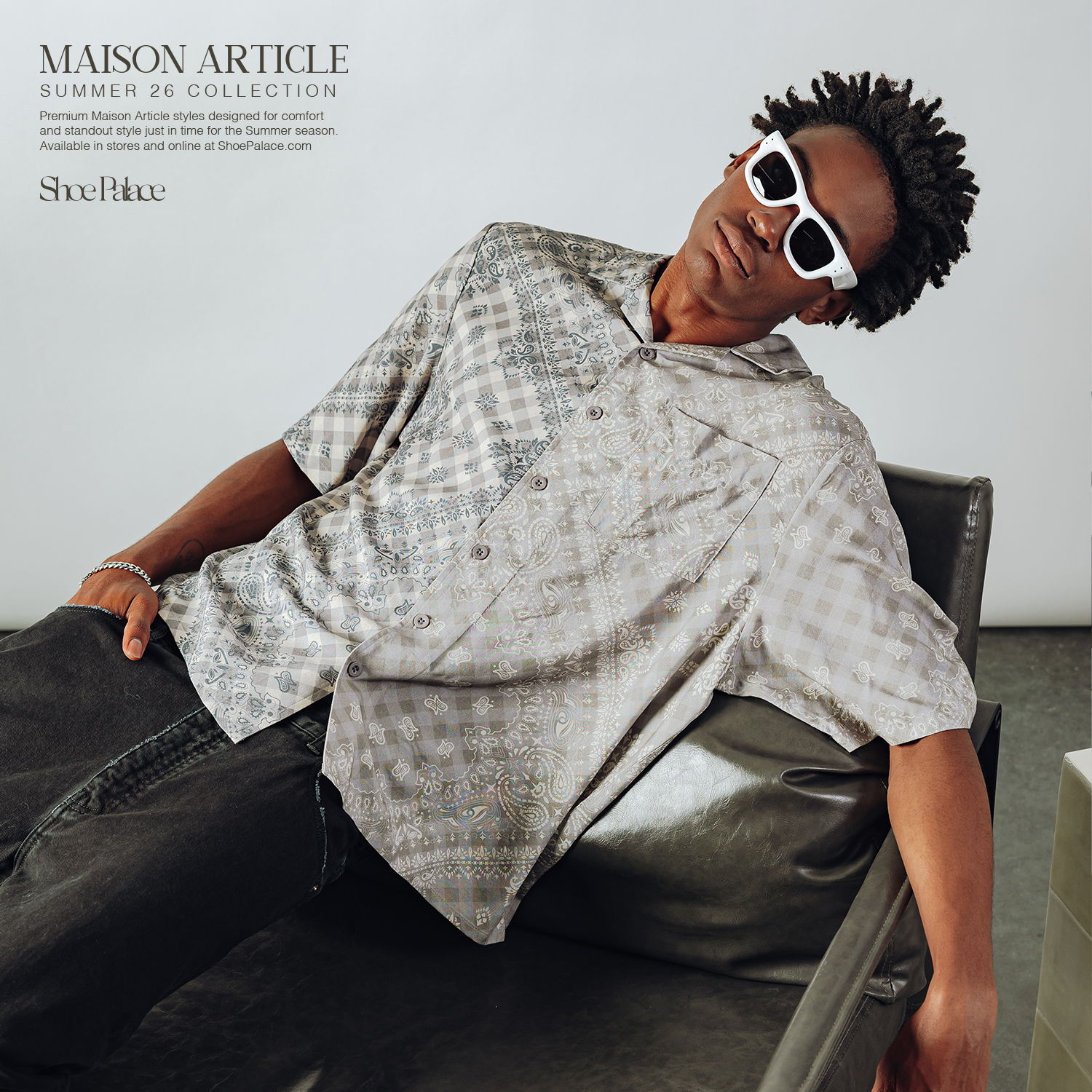 A person in a patterned shirt and sunglasses lounging on a sofa.