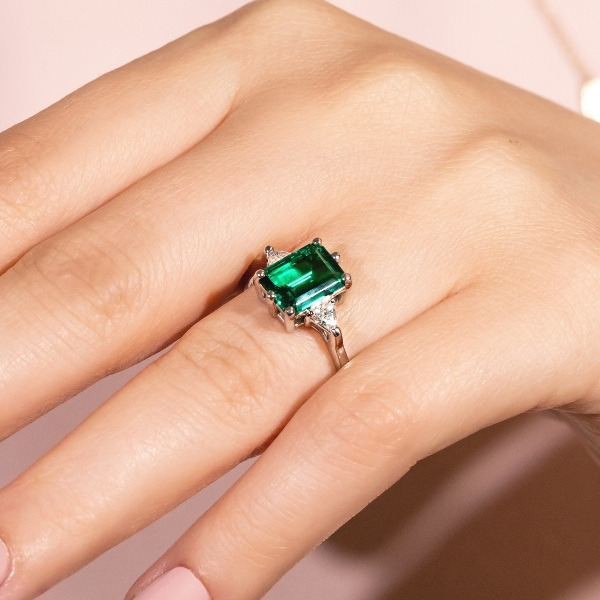 a classic looking ring with an emerald cut lab created emerald center stone with diamond side stones 