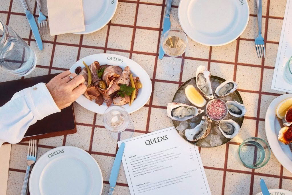 Table set with seafood dishes and plates, with a hand reaching for food.