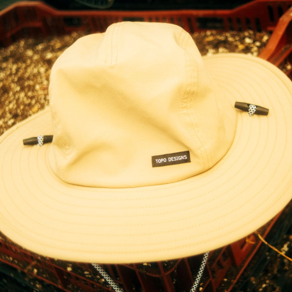 A wide-brimmed beige hat resting on a textured surface.