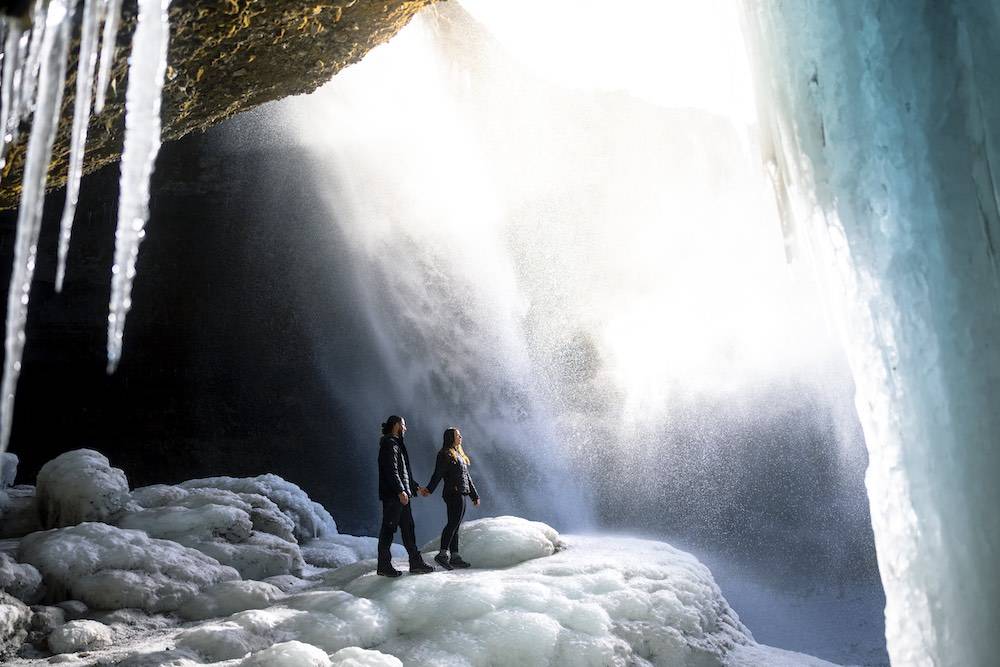 couple underneath beautiful waterfall