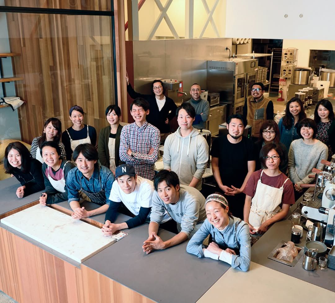 A diverse group of people smiling in a kitchen setting.