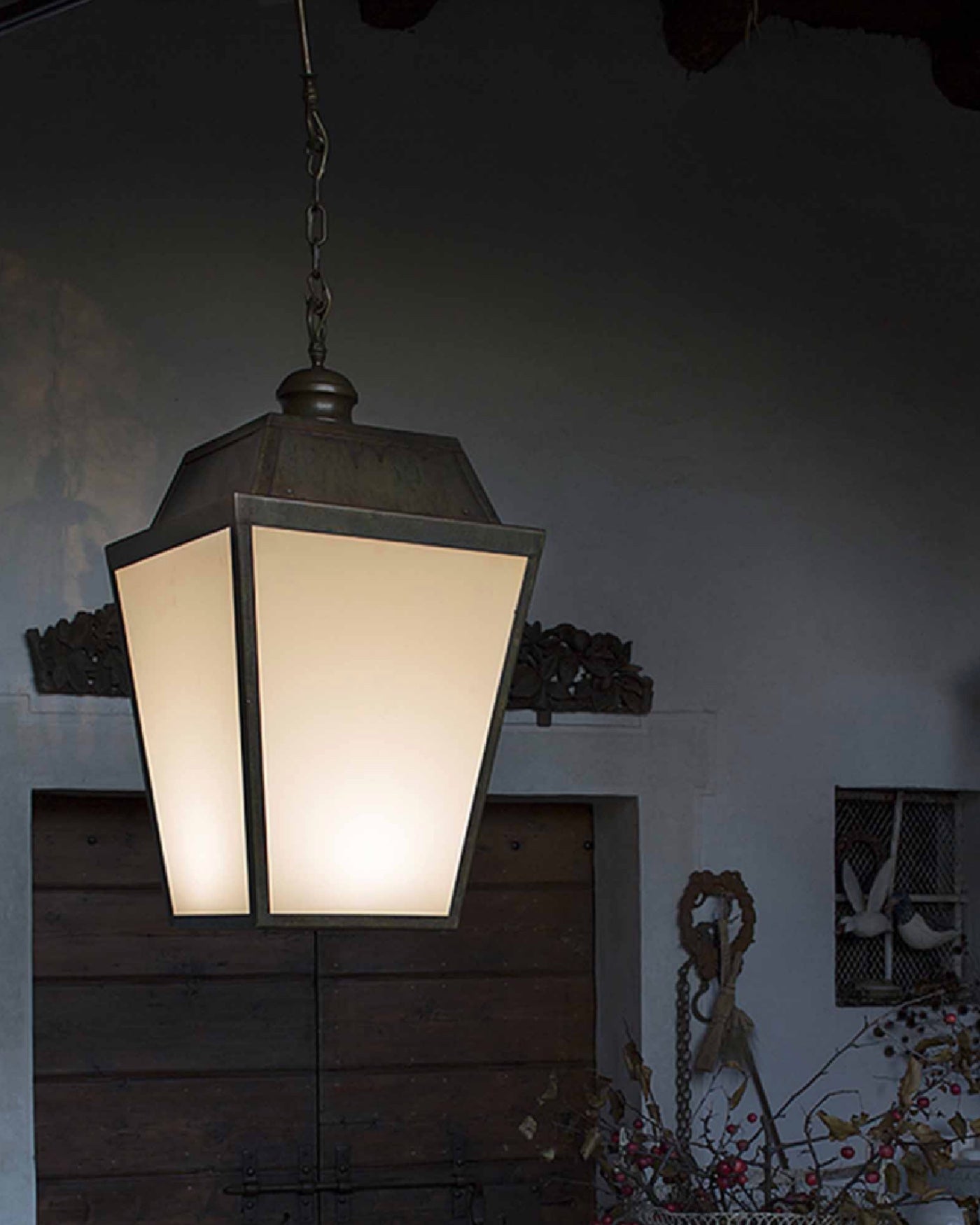 Pre-aged brass exterior lantern with white acrylic finish lightening up an entrance at night