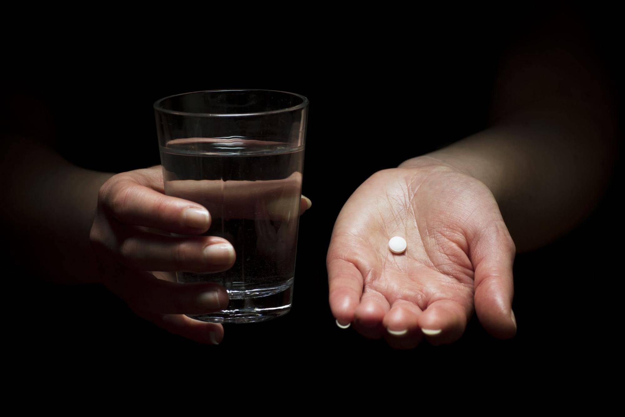 pill in hand, glass of water in other hand