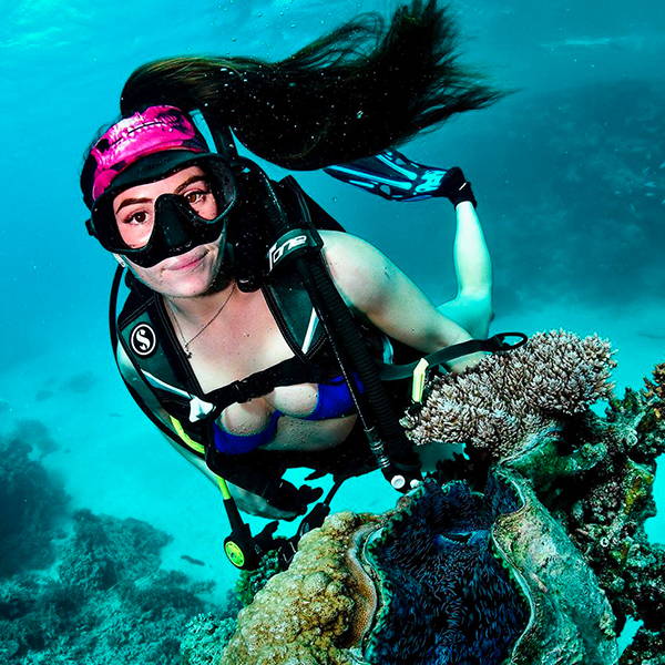 Sally Higgs snorkeling next to a reef wearing scuba gear and a face shield as a headband