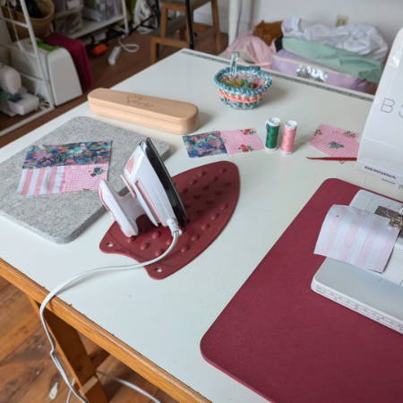 a mini iron on a sewing table resting on an iron rest