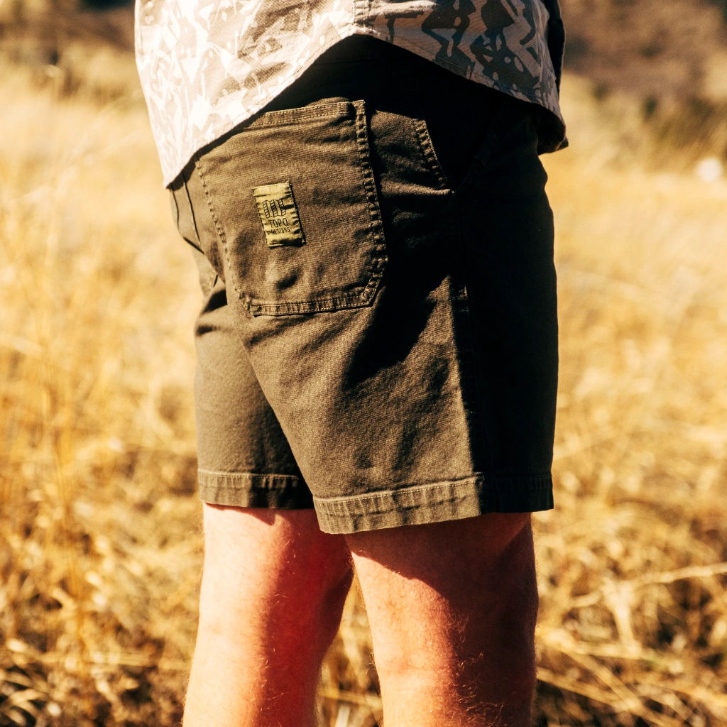 A person wearing khaki shorts in a dry, grassy field.