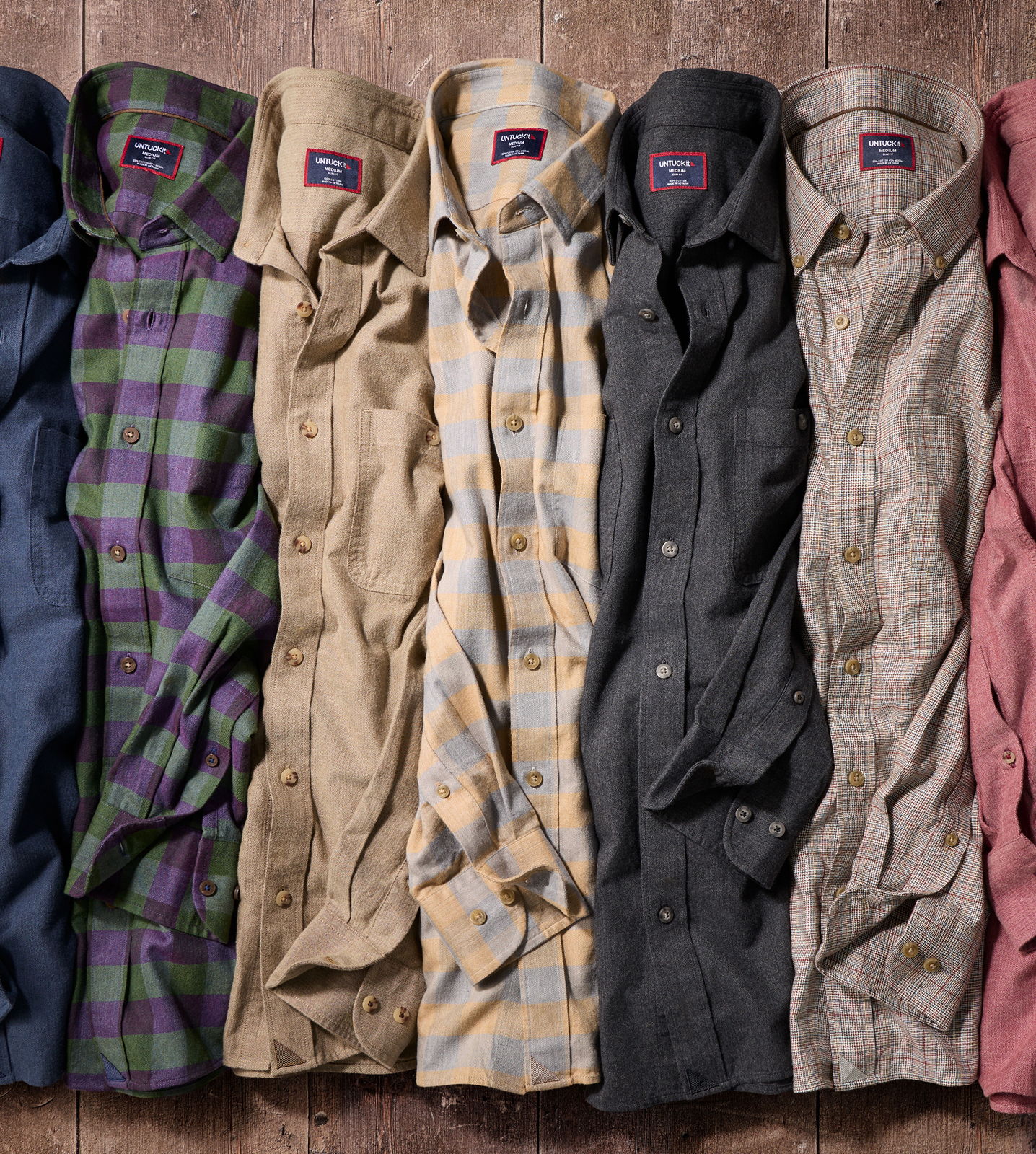 A line of various patterned and colored shirts laid flat.