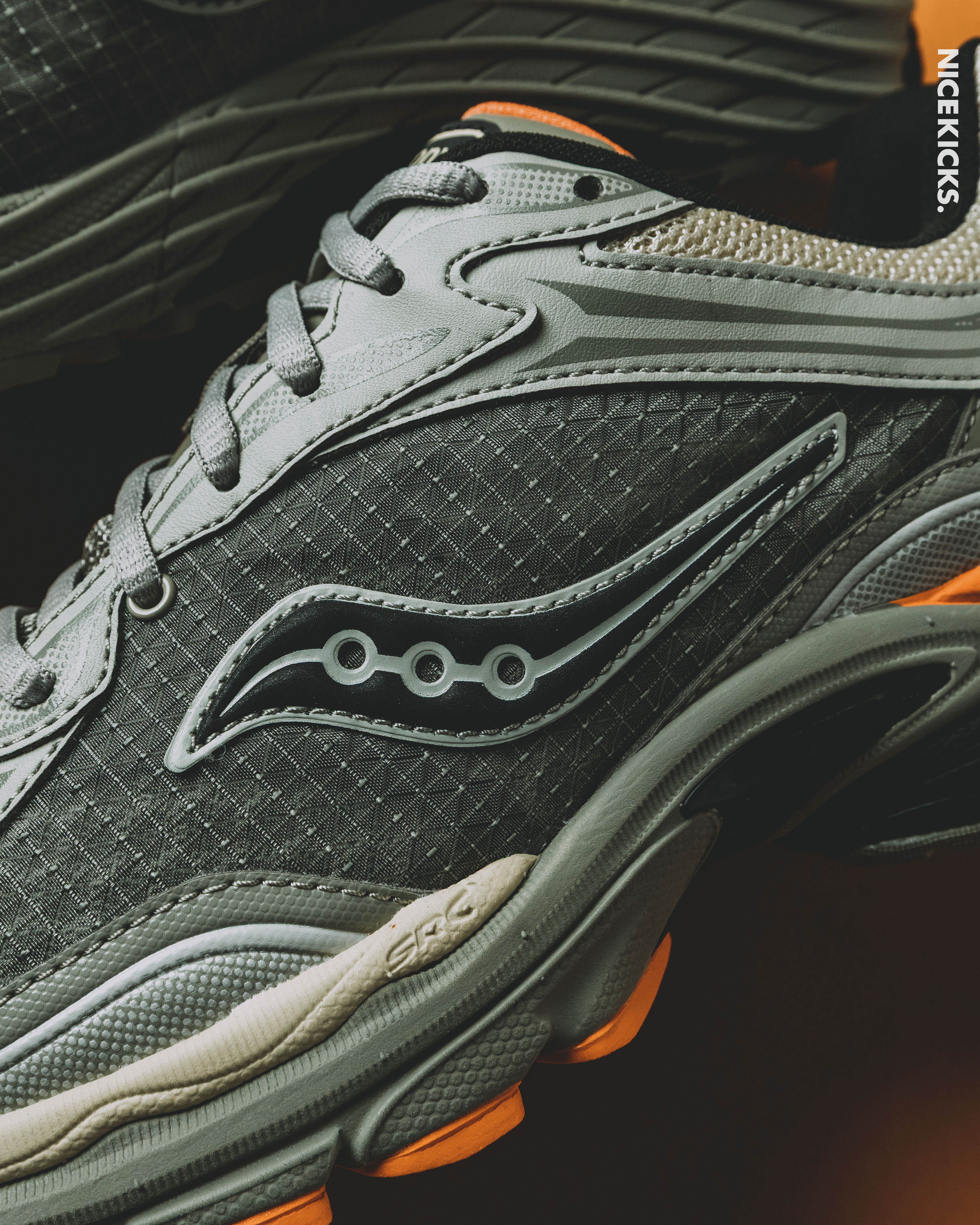 Close-up of gray Saucony sneakers with orange accents.