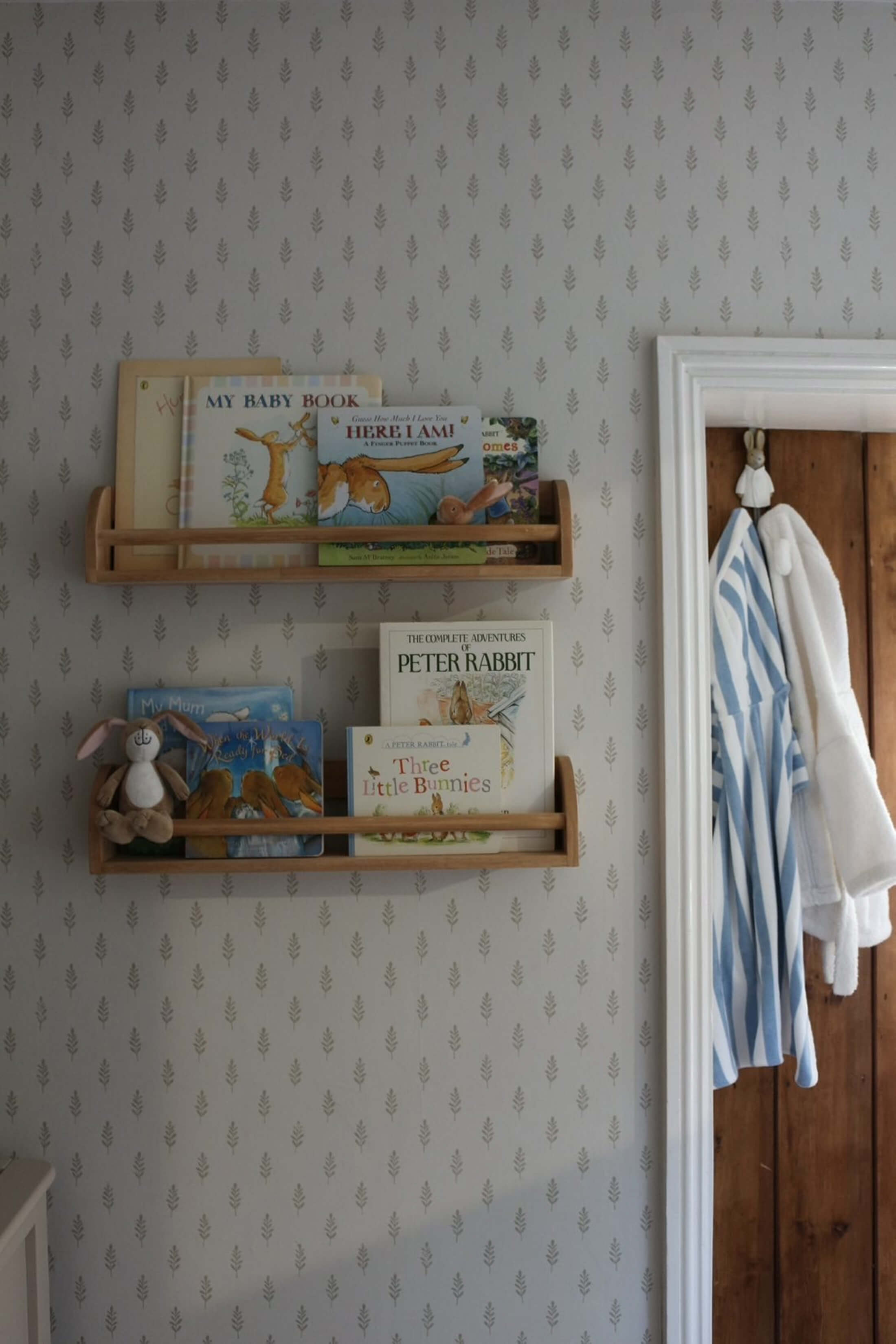 Books on wooden shelves with a striped shirt hanging nearby.