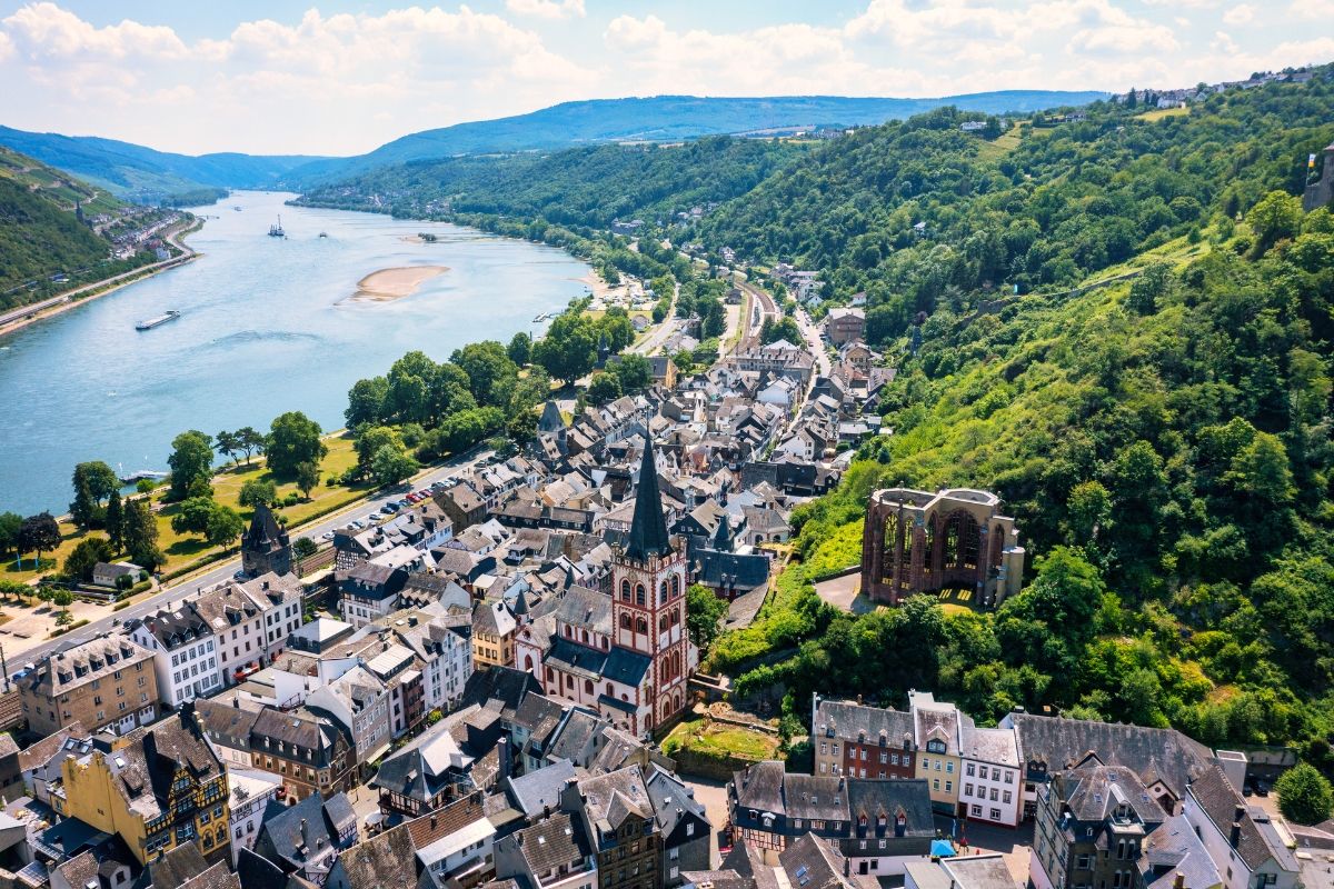 Aerial view of a town by a river surrounded by green hills.