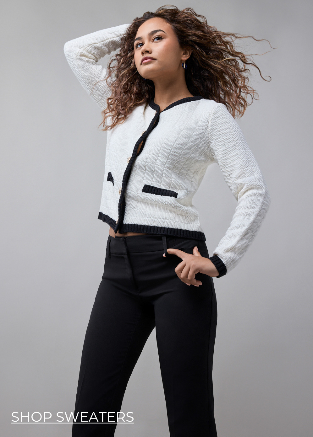 Model wearing a stylish black and white cardigan with black pants.
