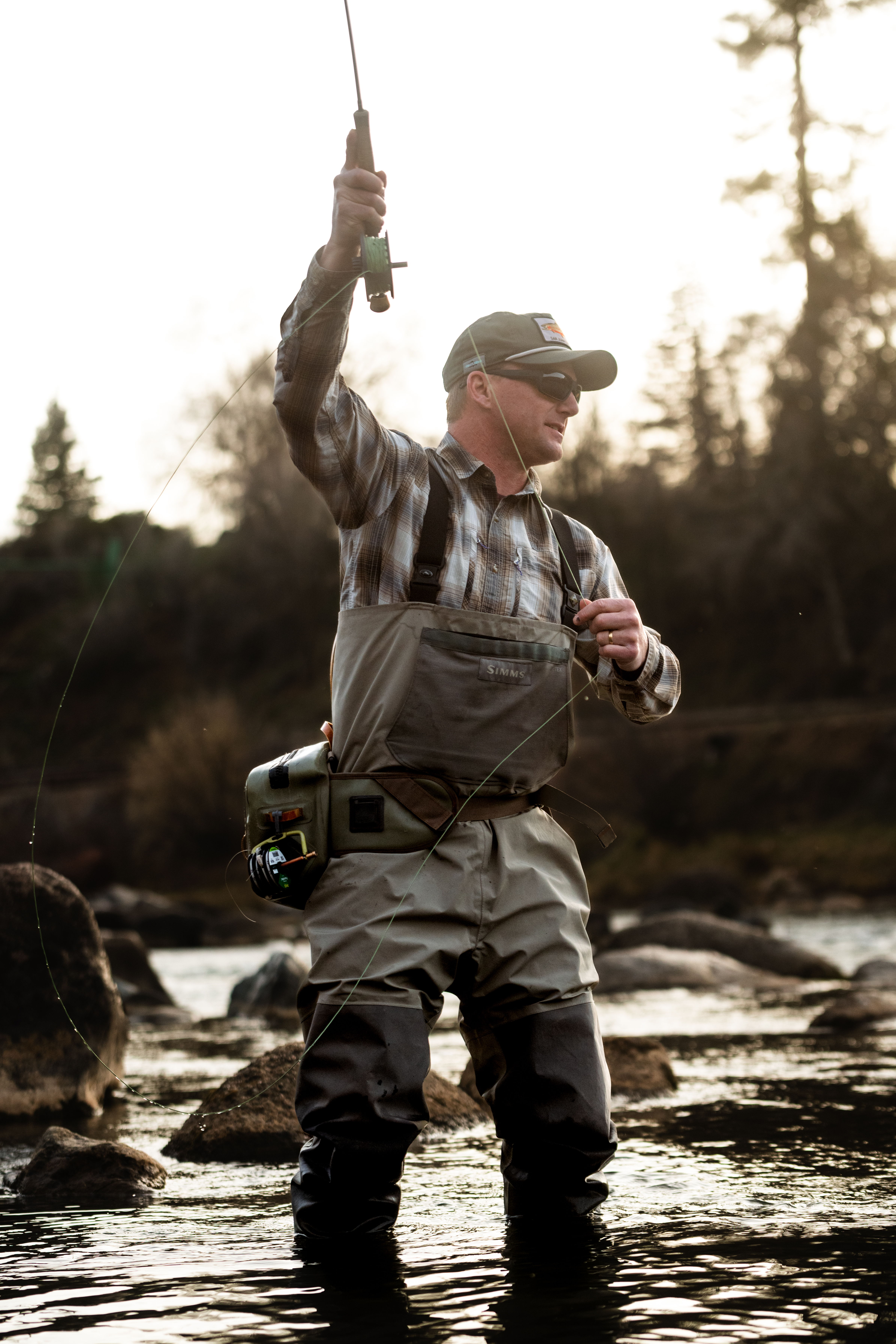 Man fishing in river, wearing The Outfitter sunglasses