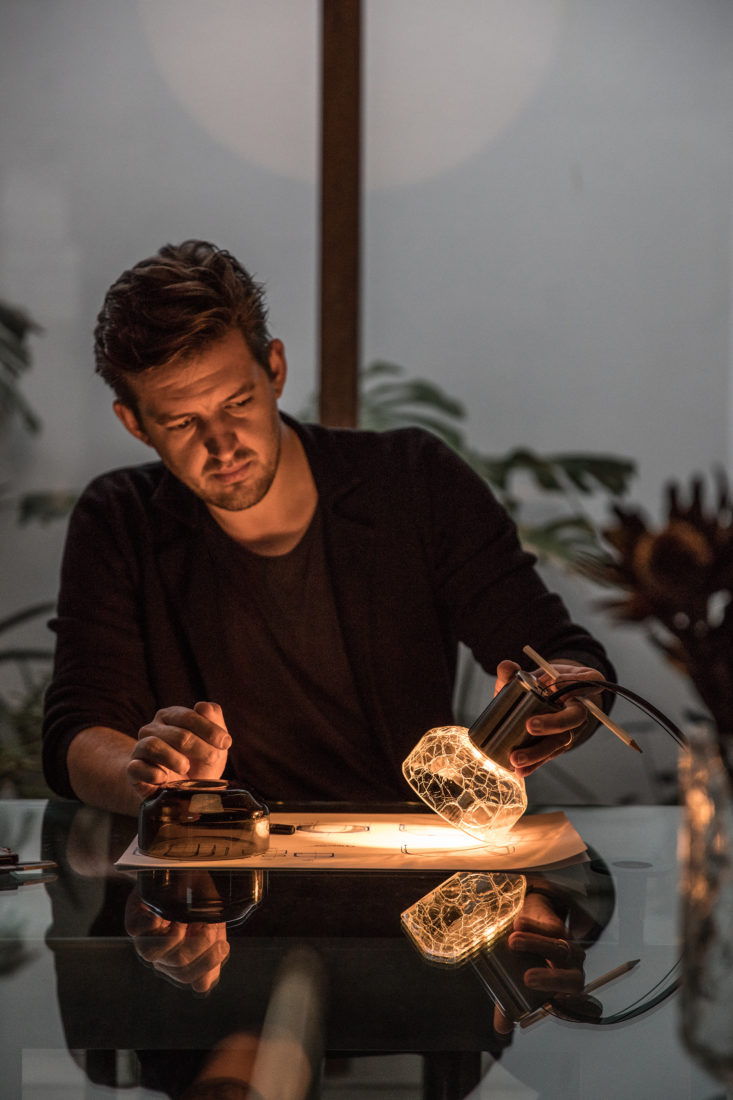 Alex Fitzpatrick lighting designer with crackle glass pendant glowing