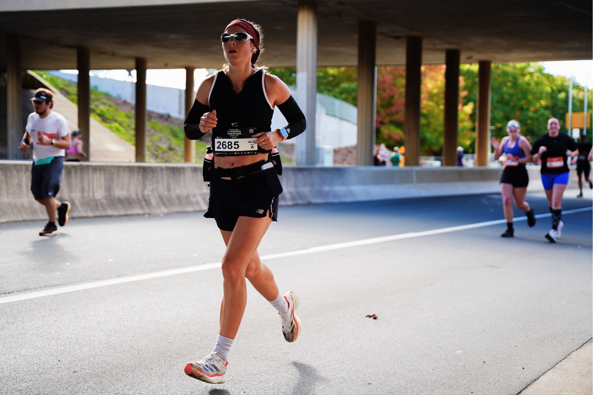 Runner in athletic gear jogging under a bridge during an event.