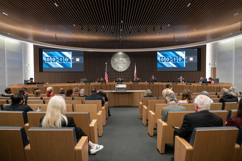 A conference room with seating, screens, and a central circular emblem.