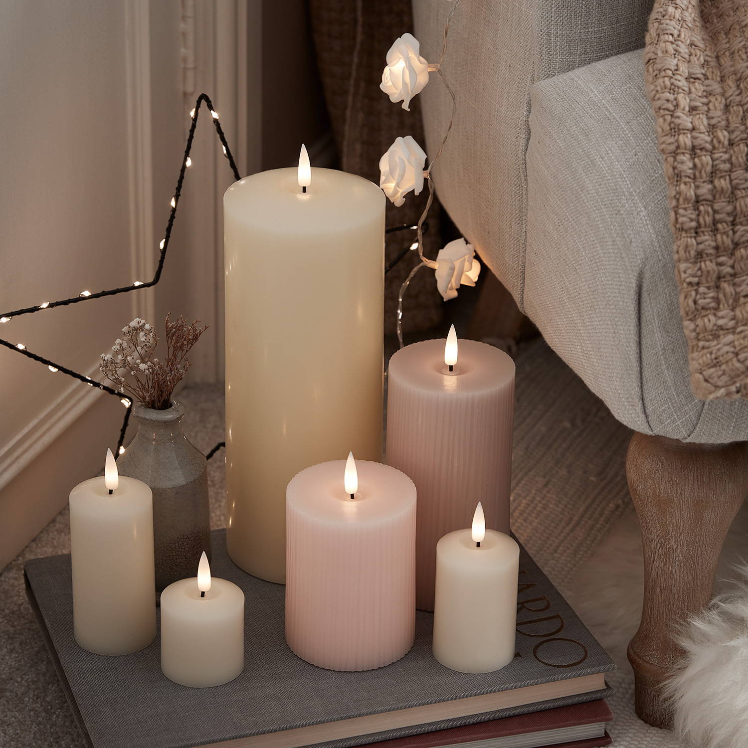 LED candles on some books next to an arm chair.