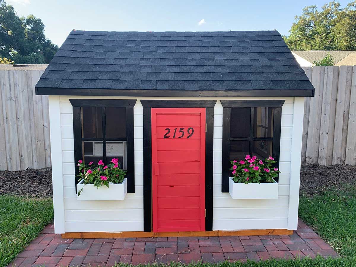 Custom Outdoor Playhouse from Front with white Flower boxes and red door by WholeWoodPlayhouses 