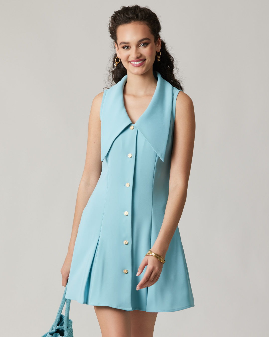 Woman wearing a sleeveless light blue dress with a large collar and buttons.