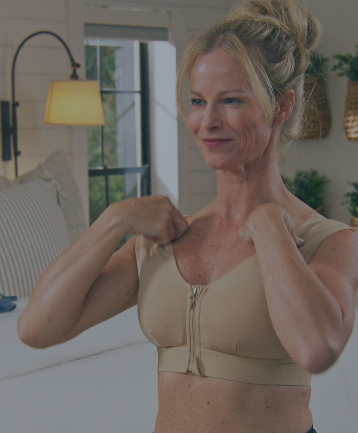 Woman putting on the Zipper Shoulder Support Bra in nude