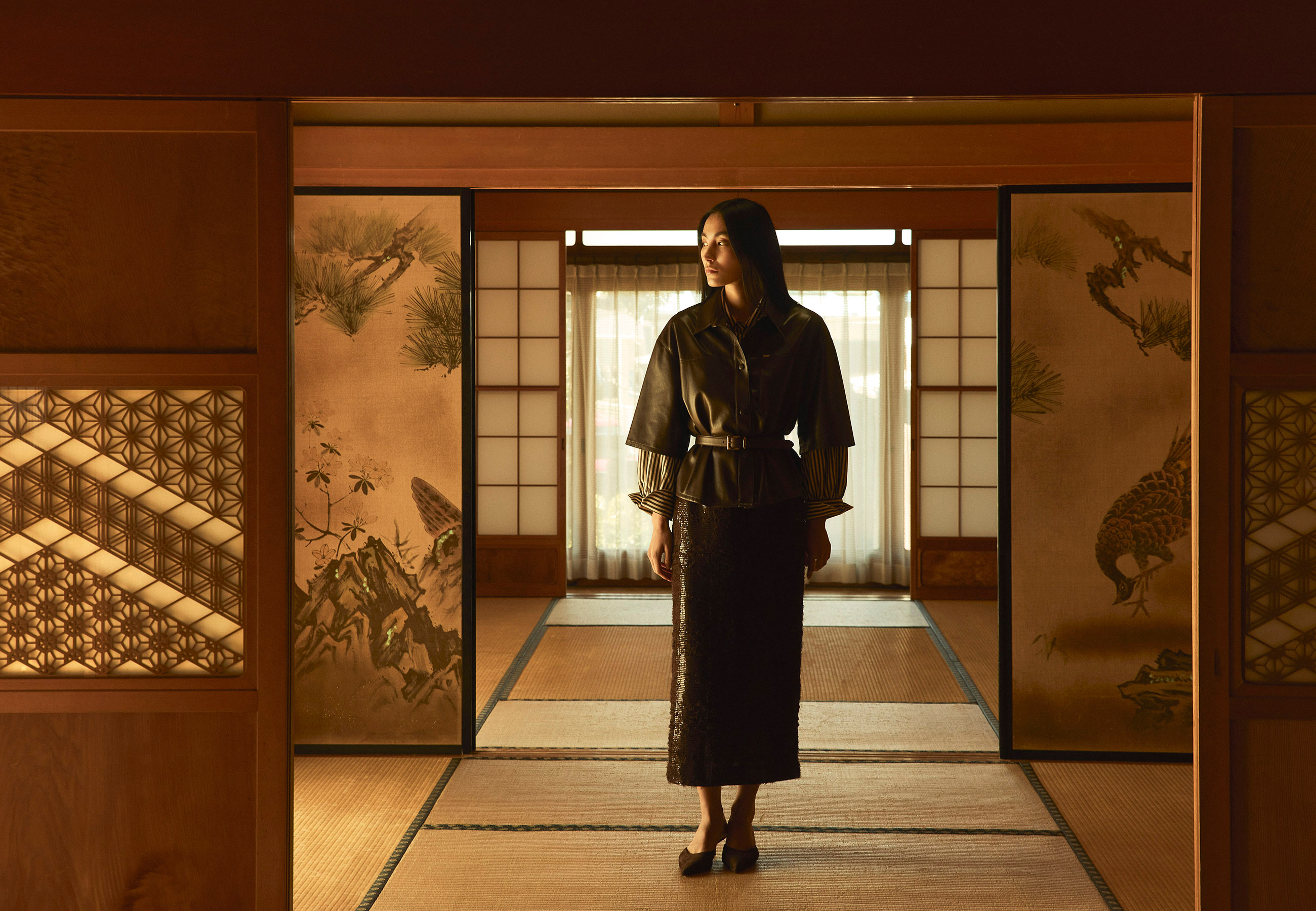 Person in traditional attire standing in a room with sliding doors.