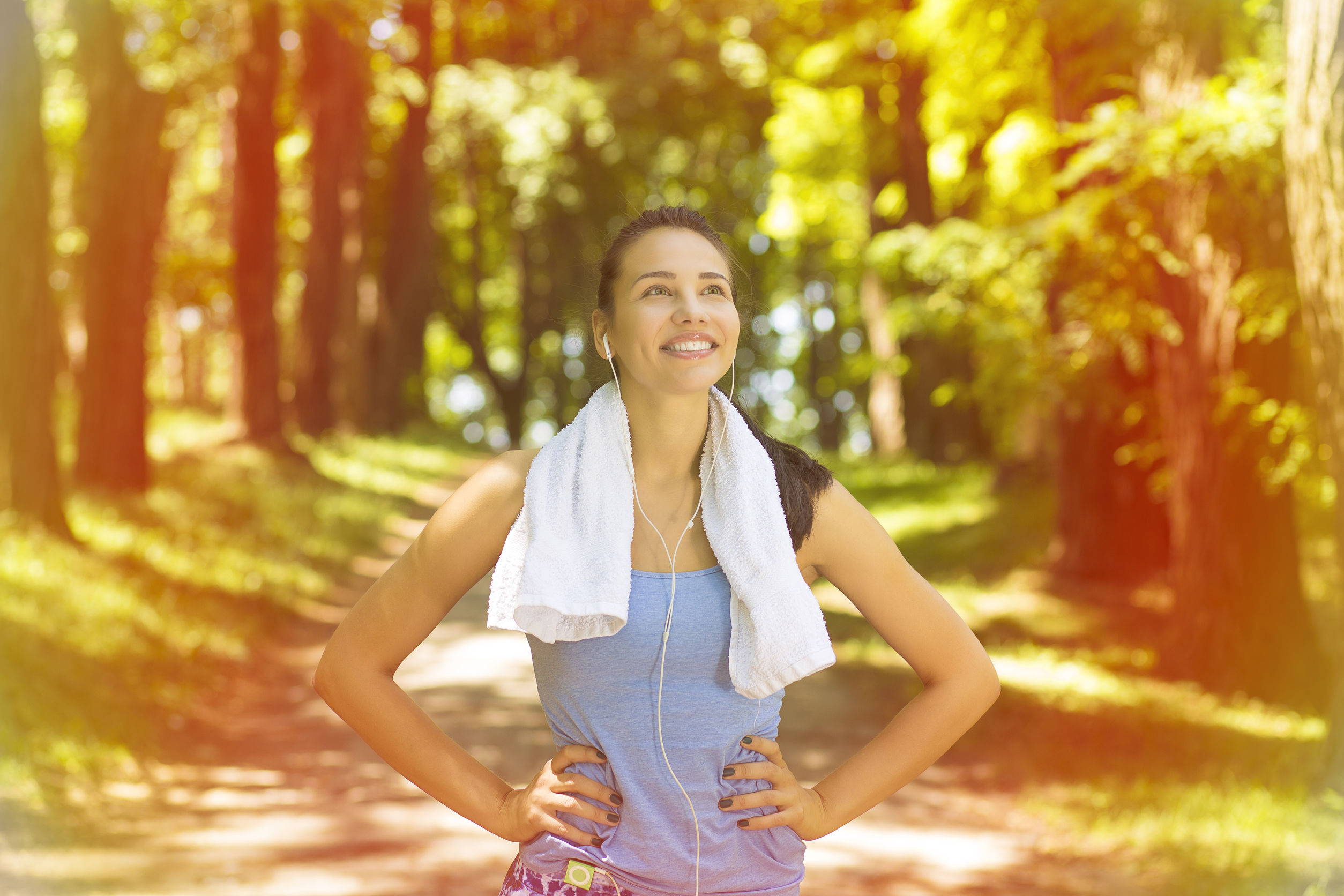 Young woman is energized after a workout and has a towel around her neck.