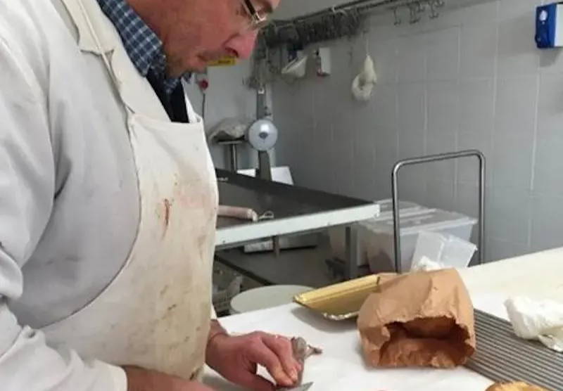 An artisan butcher cuts meat for Salumi