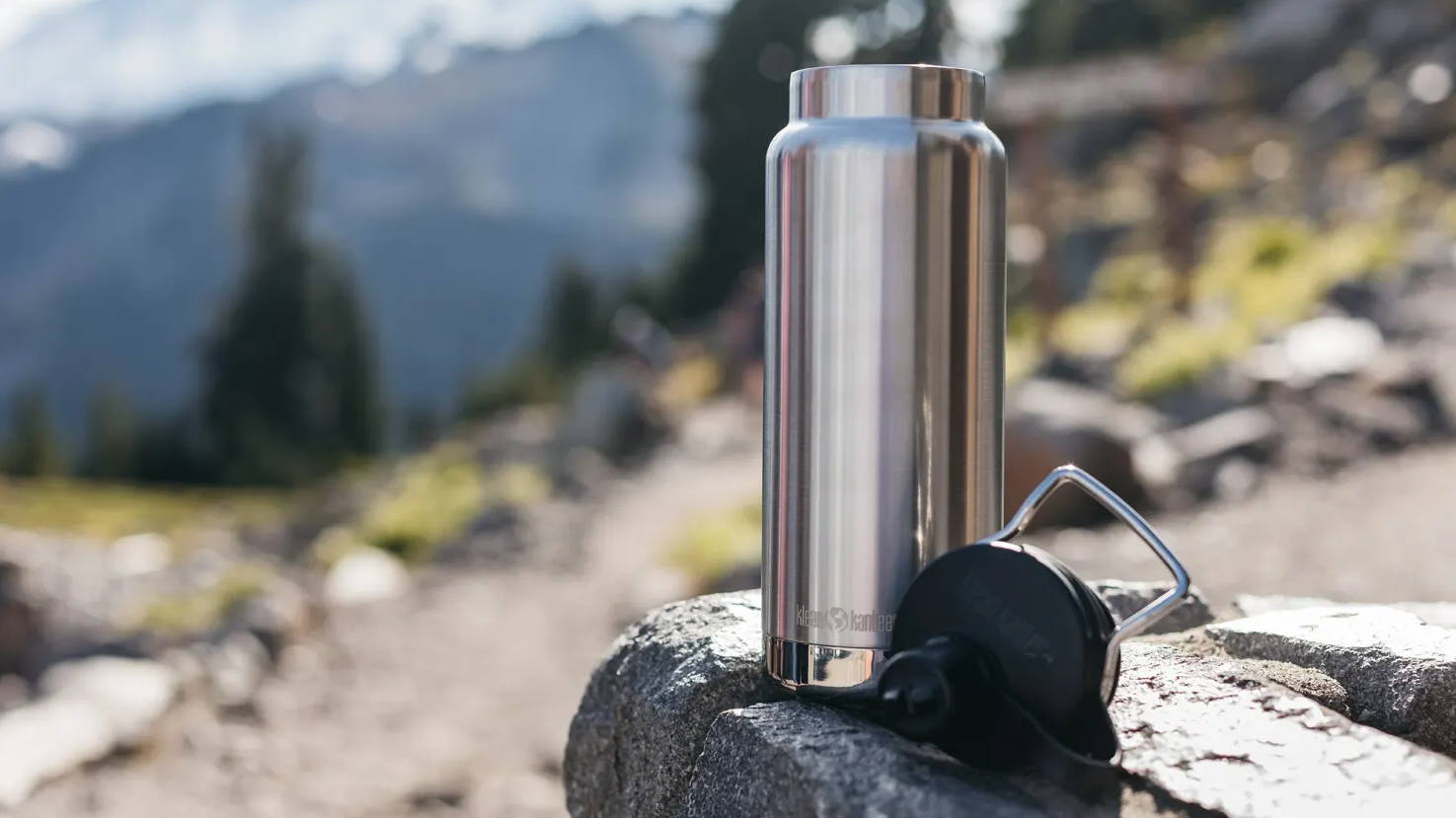 Klean Kanteen Brushed Bottle on a rock with mountain scape behind it