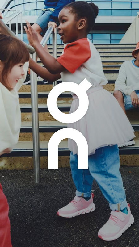 Children playing on stairs, wearing colorful clothes and sneakers. Brand logo visible.
