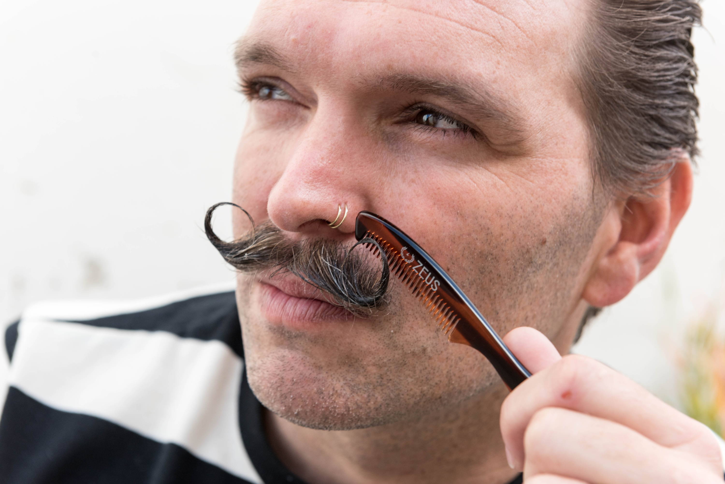 man combing mustache with zeus large mustache comb