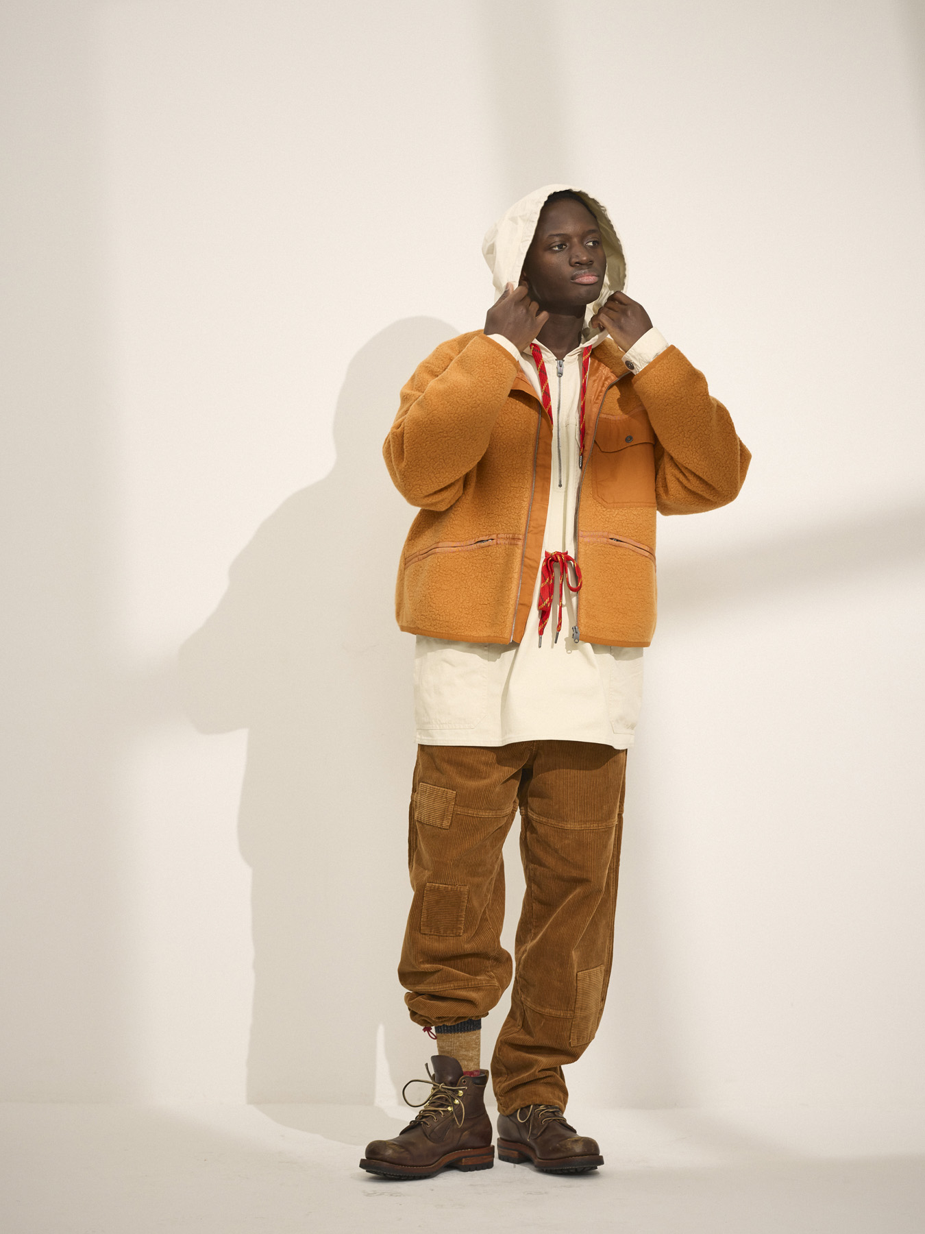 Person wearing a cream and orange outfit against a plain background.
